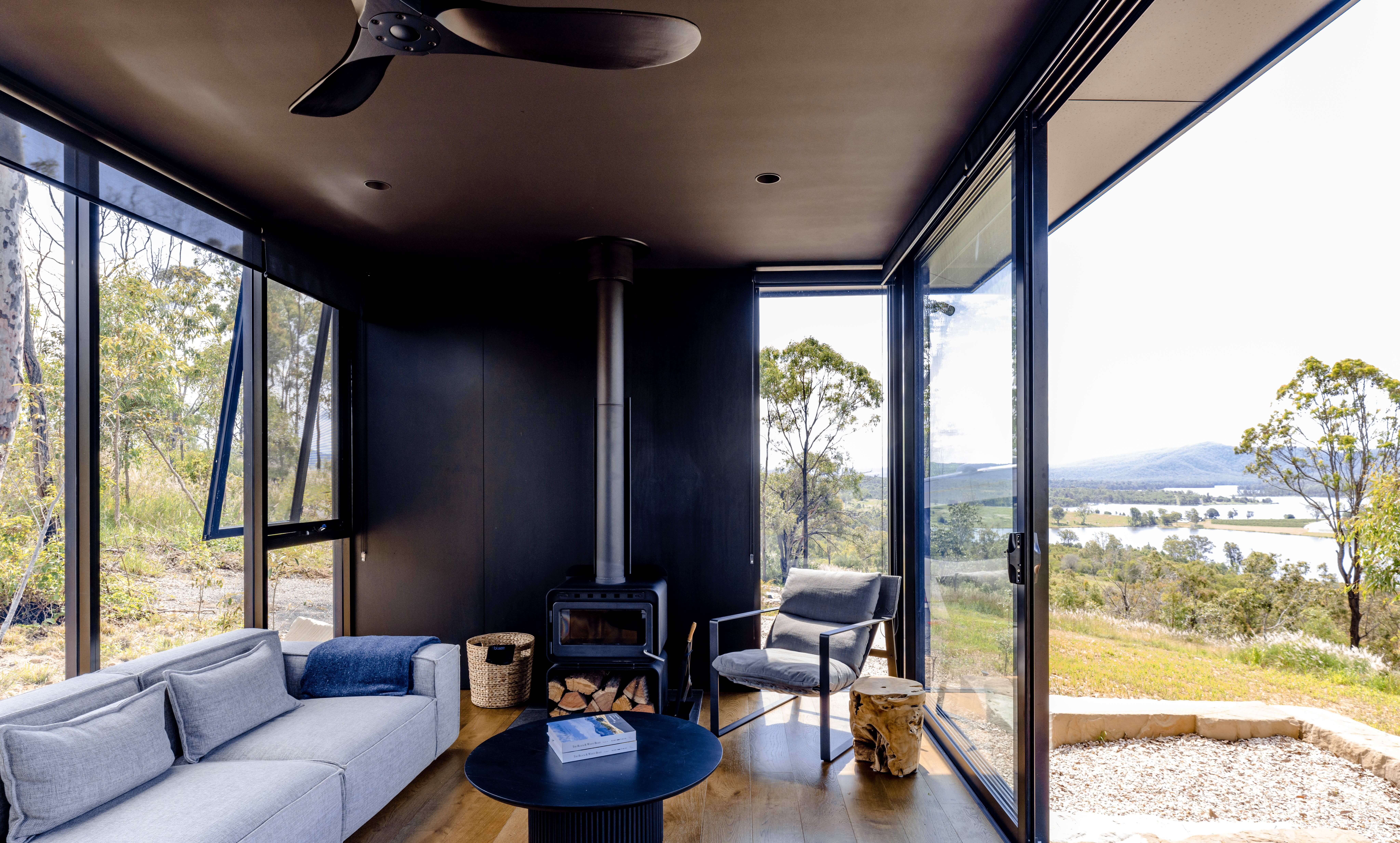 The interior of a WanderPod accommodation, looking out onto native Australian bushland and tranquil Lake Wyralong