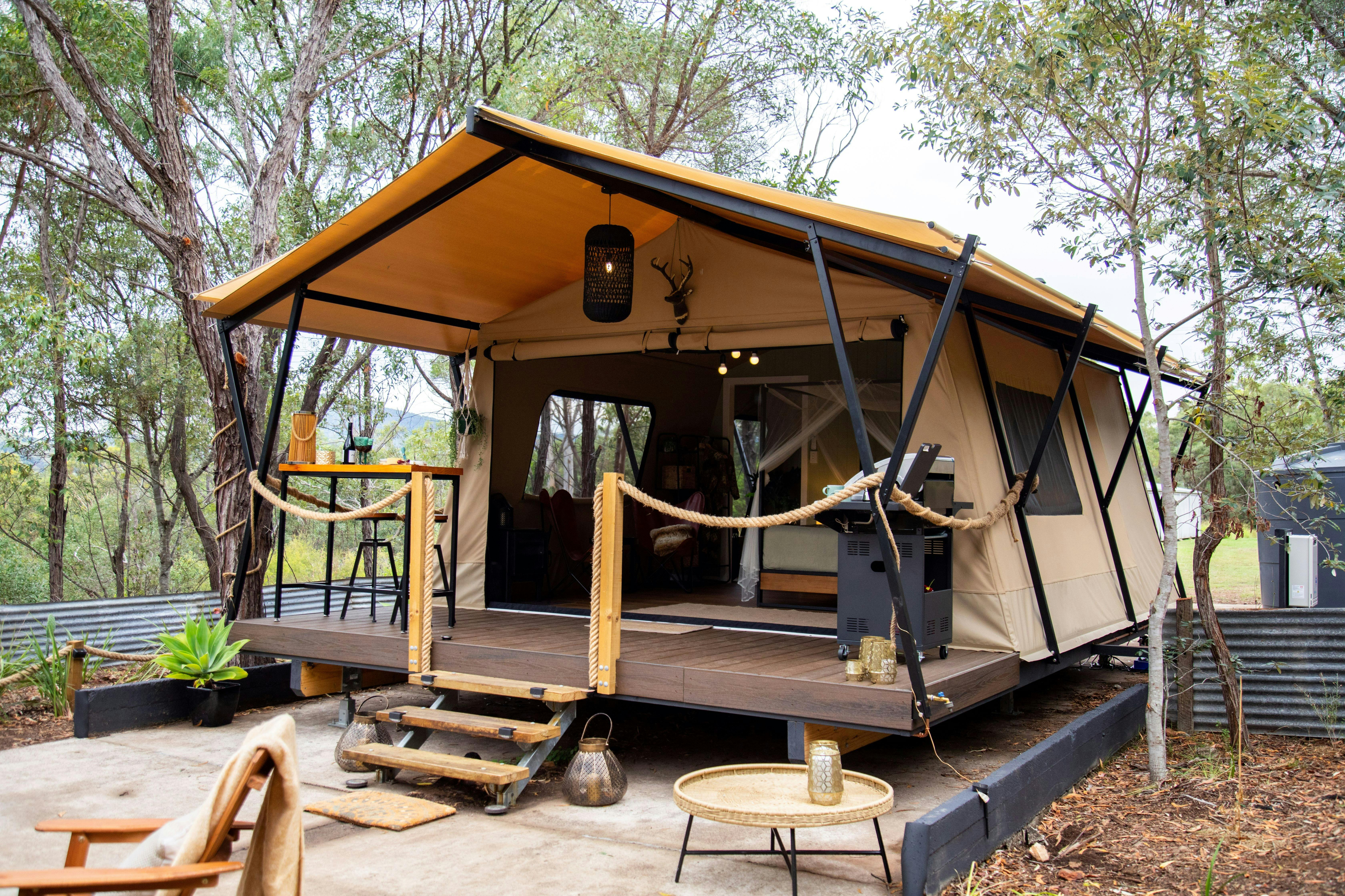 a picture of a luxury safari tent with deck and stairs set in a bush setting