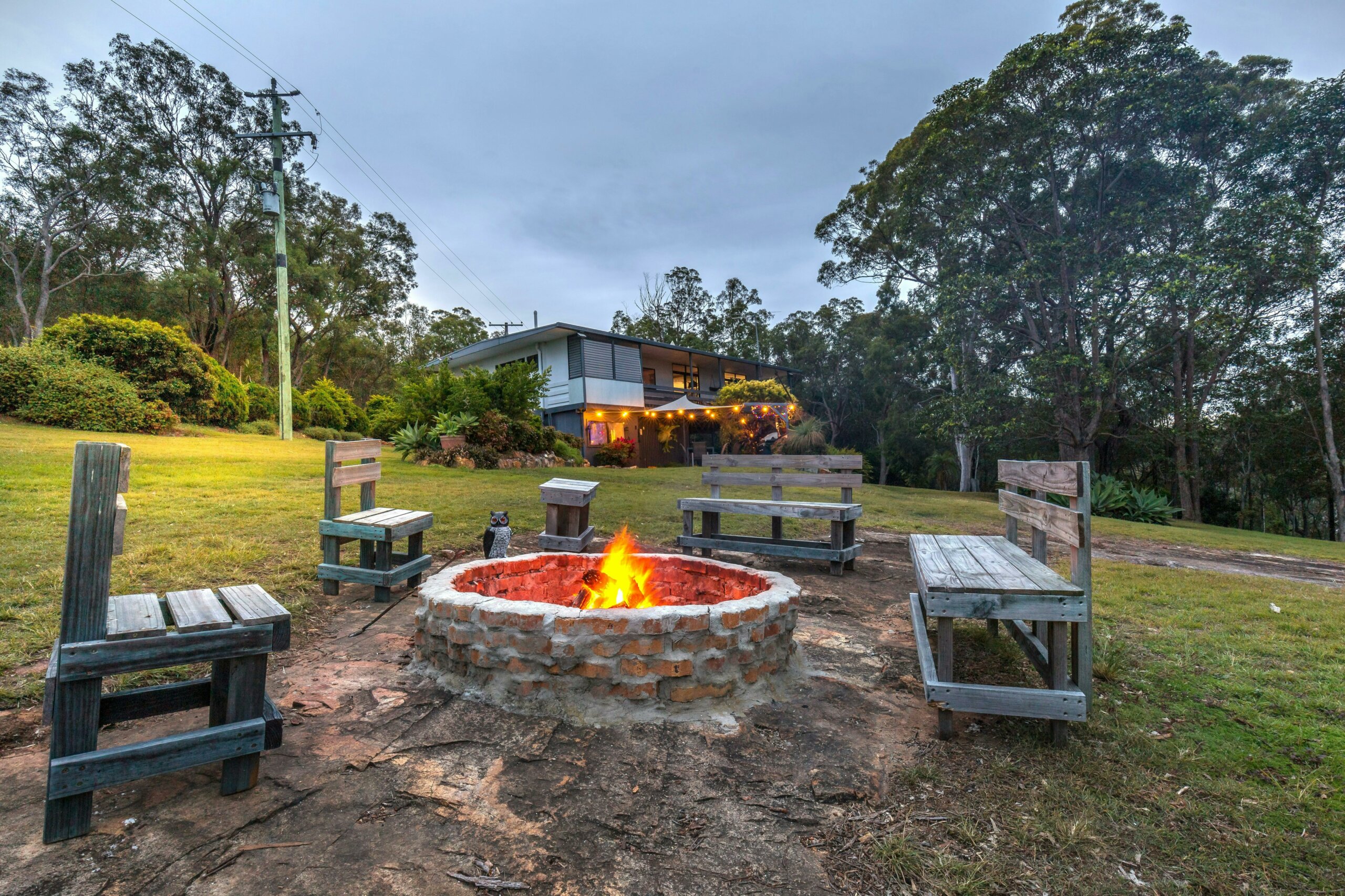 a firepit lit with seating around and house in the distance