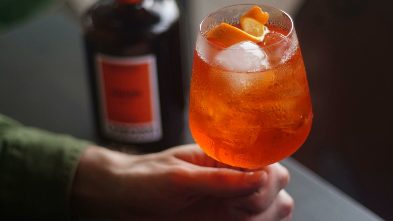 A hand holding a Loborn Amaro Spritz