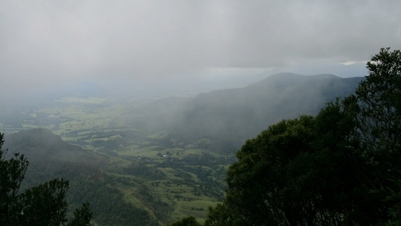 View over valley to distant mountain, shrouded in fog.