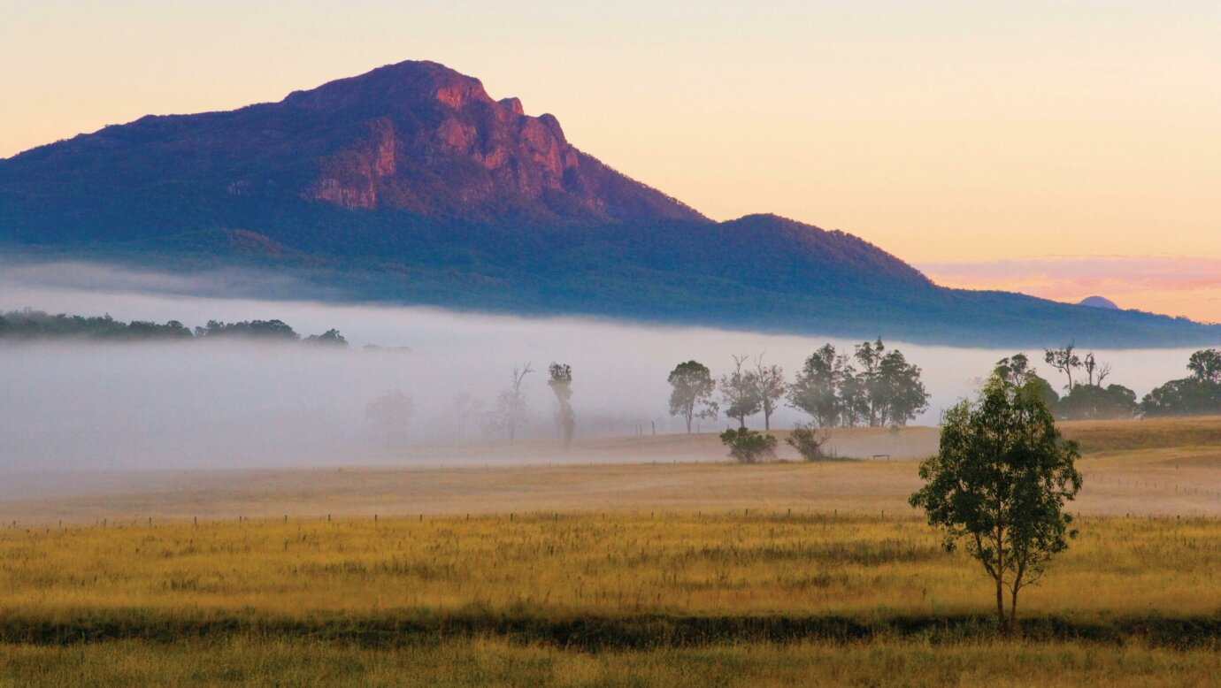 Mount Maroon glowing in sunlight with fog in foreground.