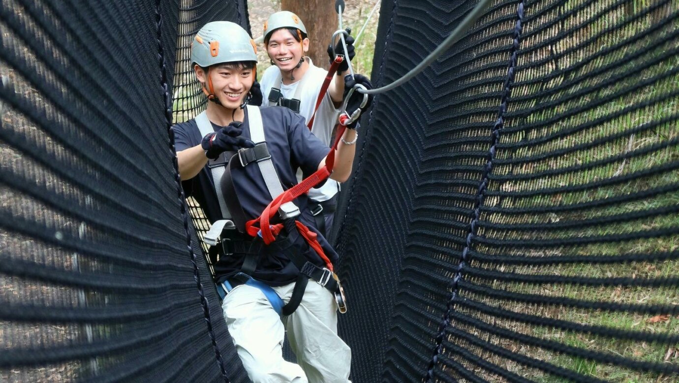 2 Gentleman climbing through a net game on the high ropes adventure park