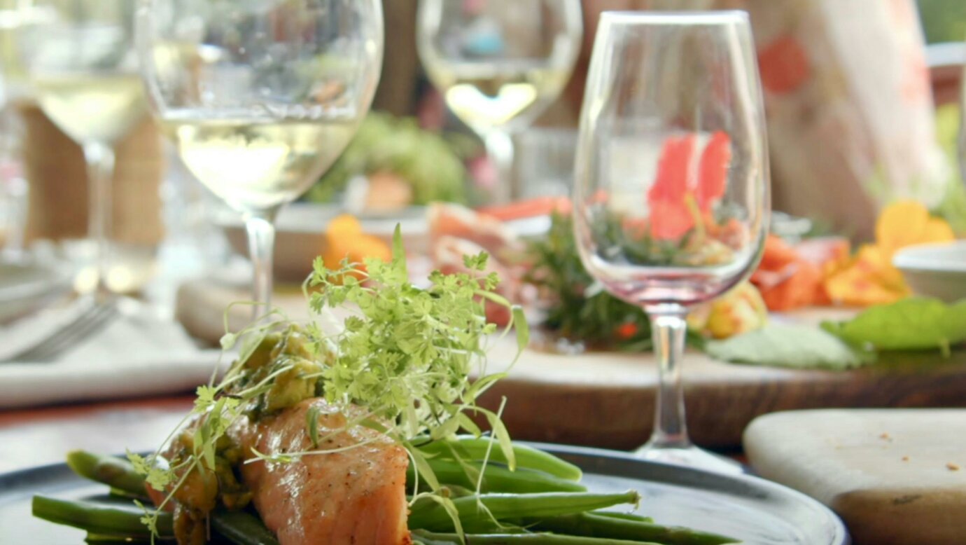 A plate of salmon with green beans and potatoes with glasses of wine on the table