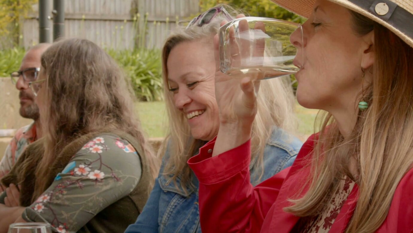 A group of women sitting at a winery smiling and sipping wine