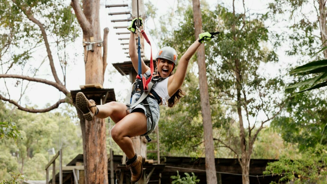 Woman ecstatic as she flies across a zipline.