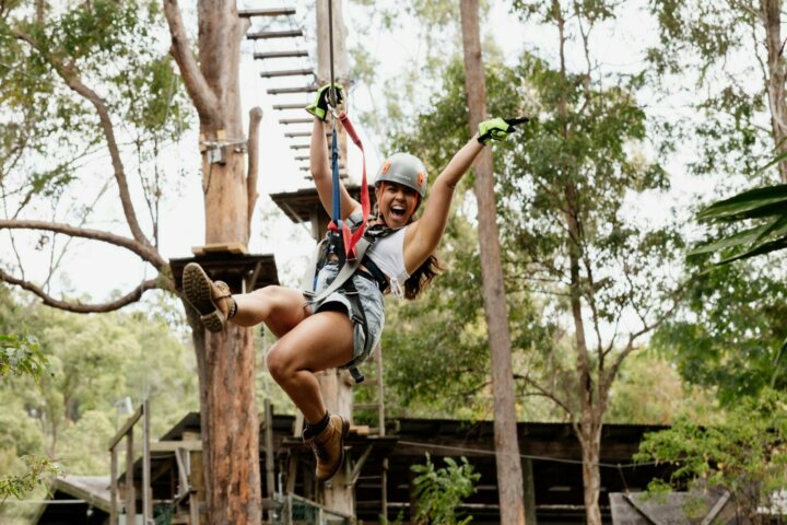 Woman ecstatic as she flies across a zipline.